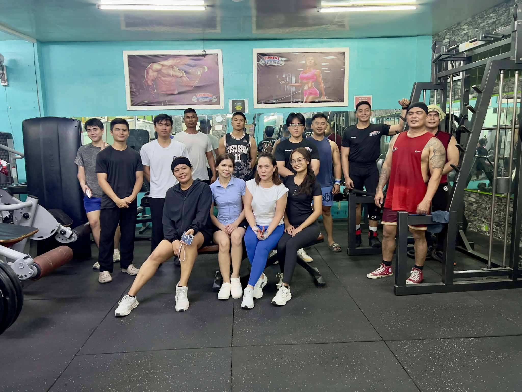 Gym regulars sitting and standing around a bench