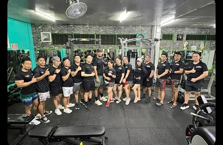 Members in matching black shirts giving a thumbs up